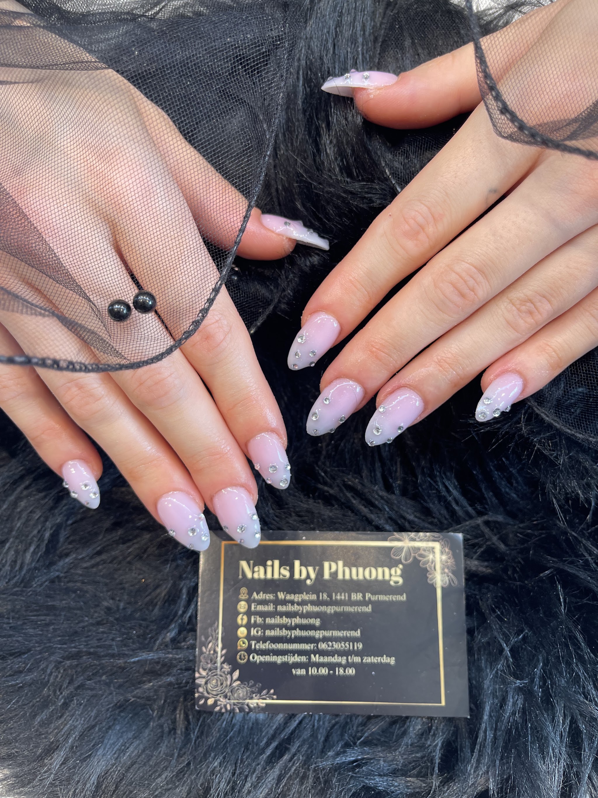 Lila amandelnagels met glitter en steentjes, met het visitekaartje van de salon