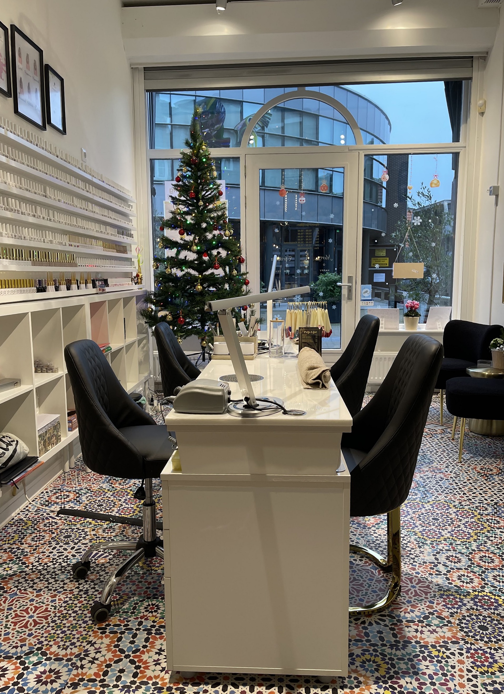 De manicuretafel van de salon, met zwarte stoelen, de lakjeswand en de mozaïekvloer