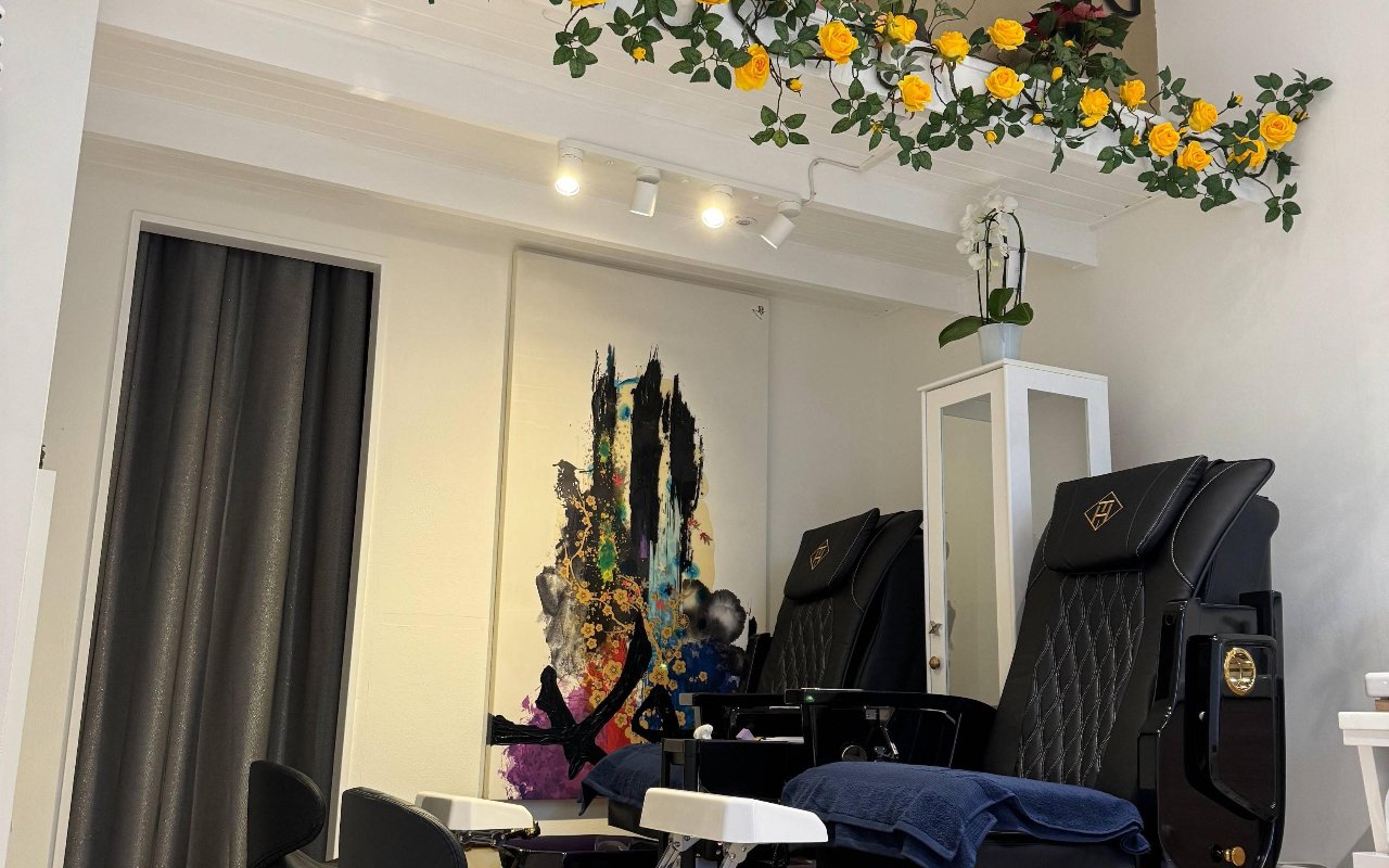 De pedicurehoek met twee zwarte massagestoelen en bloemen aan het plafond