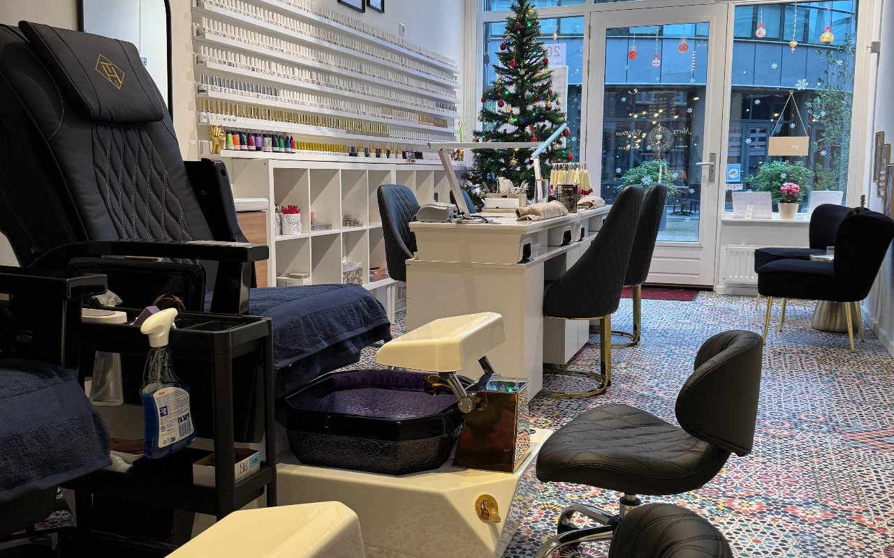 Het interieur van de salon: pedicurestoel, manicuretafel en de lakjeswand