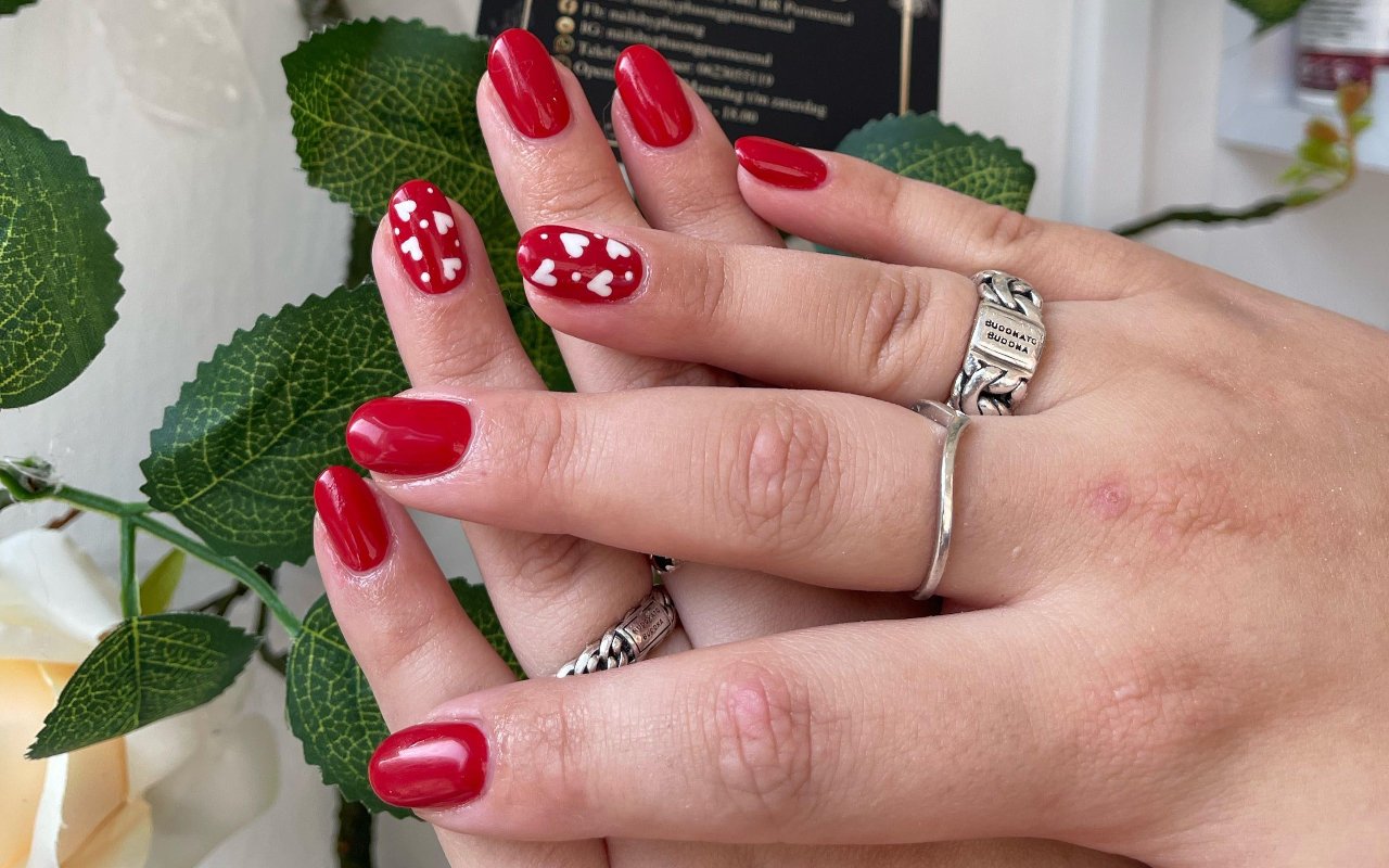 Rode nagels met een hartjesaccent, tussen rozen en bladeren